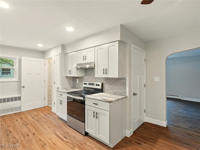 kitchen featuring radiator heating unit, stainless steel electric range, under cabinet range hood, a baseboard radiator, and light wood-style flooring