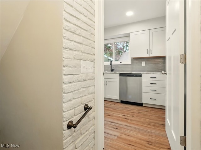 kitchen featuring white cabinets, dishwasher, light countertops, light wood-style flooring, and tasteful backsplash