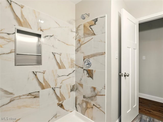 full bathroom featuring baseboards, a marble finish shower, and wood finished floors