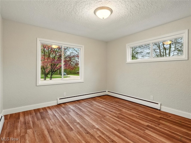 unfurnished room with baseboards, baseboard heating, a textured ceiling, and wood finished floors