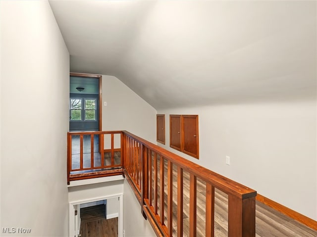 interior space featuring baseboards, vaulted ceiling, wood finished floors, and an upstairs landing