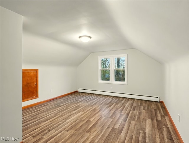 additional living space with baseboards, a baseboard heating unit, wood finished floors, and lofted ceiling