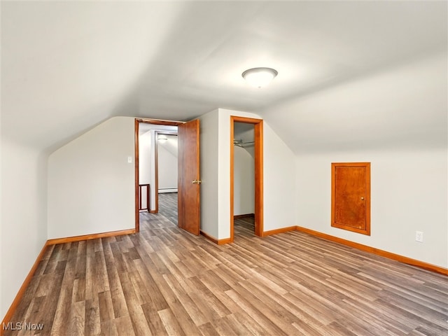 additional living space with baseboard heating, baseboards, wood finished floors, and lofted ceiling