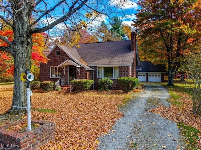 bungalow-style house with brick siding, a garage, and a chimney