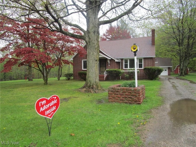 view of front facade with brick siding, roof with shingles, a front yard, and a chimney