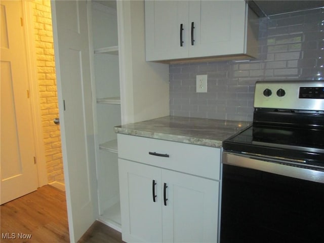 kitchen with backsplash, light wood finished floors, white cabinetry, and electric stove