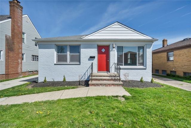 view of front of house featuring brick siding, a front yard, and entry steps