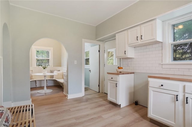 460 Carthage Ave, Kent, OH 44240 - kitchen featuring white cabinets, arched walkways, decorative backsplash, and light wood-type flooring