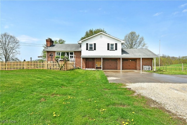 split level home with brick siding, driveway, fence, and a front lawn