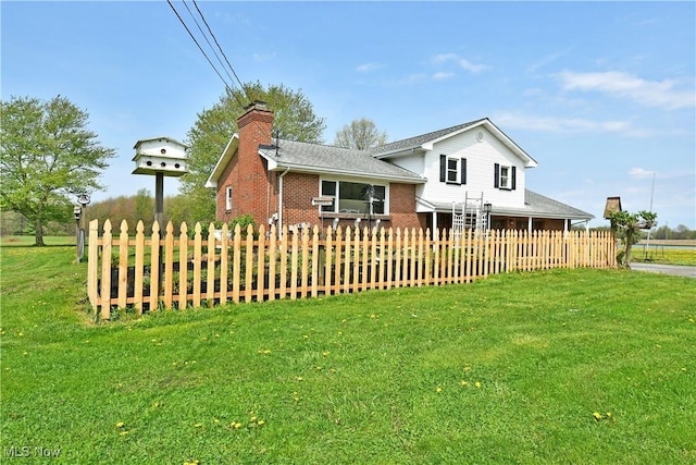 split level home featuring fence, a chimney, a front lawn, and brick siding