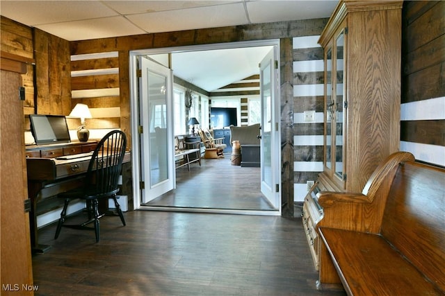 home office with wooden walls, french doors, vaulted ceiling, and wood finished floors