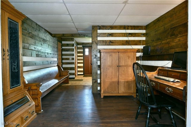 office area featuring wooden walls, dark wood finished floors, and a paneled ceiling
