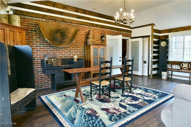 dining area with brick wall, wood finished floors, and a notable chandelier