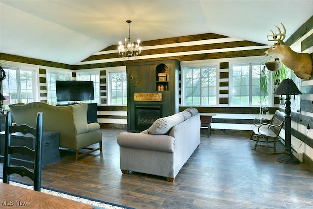 living area featuring wood finished floors, vaulted ceiling, an inviting chandelier, and a fireplace