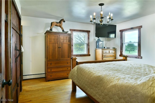 bedroom with a chandelier, a baseboard heating unit, and light wood-type flooring