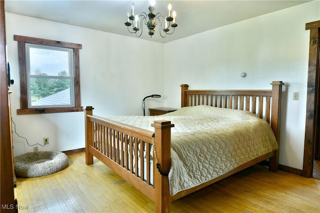 bedroom with an inviting chandelier, baseboards, and hardwood / wood-style floors
