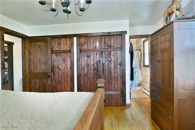 bedroom with baseboard heating, light wood-style flooring, and a notable chandelier