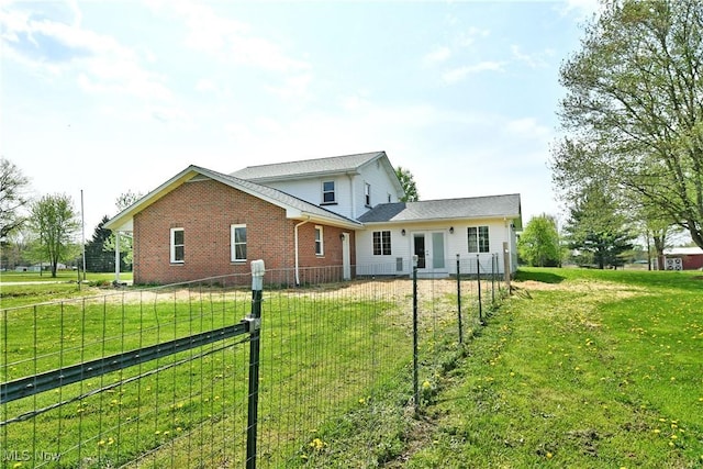 rear view of property with brick siding, a fenced backyard, a lawn, and french doors