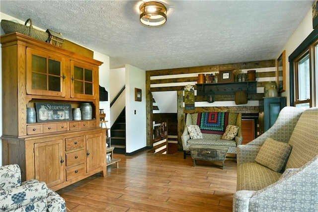 living area with a textured ceiling, stairs, and hardwood / wood-style floors