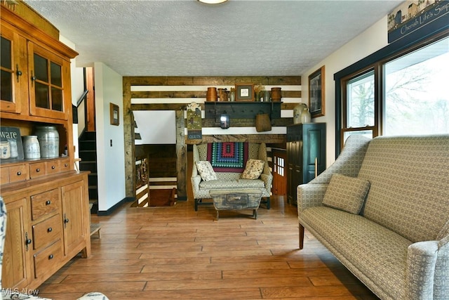 sitting room with wood-type flooring, wood walls, and a textured ceiling