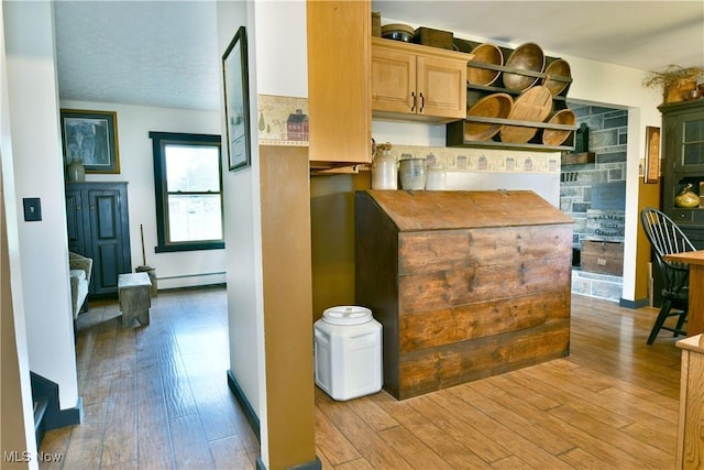 kitchen with light wood-style floors, light brown cabinetry, a baseboard heating unit, and tasteful backsplash