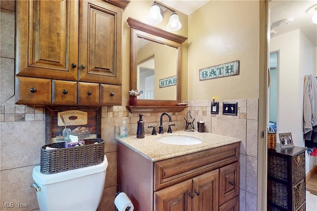 bathroom featuring vanity, toilet, and tile walls