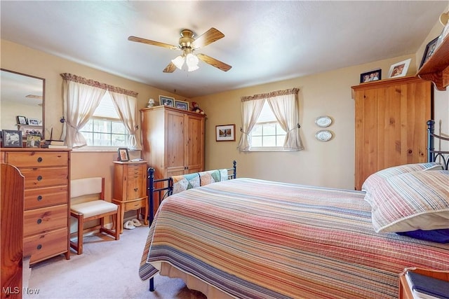 bedroom featuring a ceiling fan, light colored carpet, and multiple windows