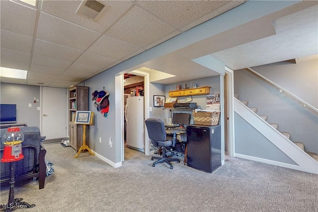 carpeted office space with baseboards, a paneled ceiling, and visible vents