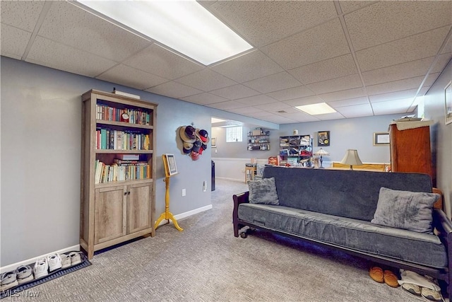 carpeted living area with baseboards and a drop ceiling