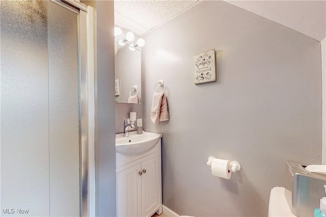 full bathroom with vanity, a textured ceiling, and a shower stall