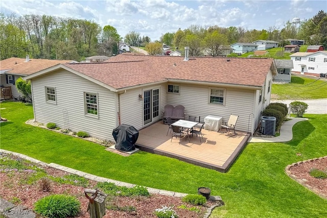 rear view of house featuring a yard, cooling unit, a wooden deck, and roof with shingles