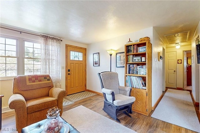 living area with baseboards, attic access, and wood finished floors