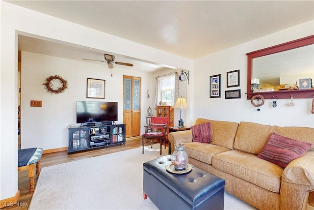 living area with a ceiling fan, baseboards, and wood finished floors