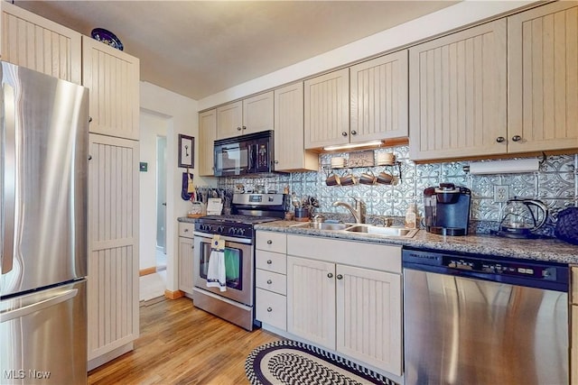 kitchen with light wood-style floors, baseboards, tasteful backsplash, a sink, and appliances with stainless steel finishes