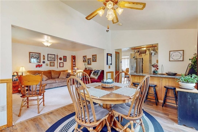 dining area featuring a ceiling fan, light wood finished floors, and vaulted ceiling