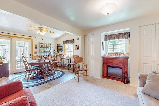 living area featuring a glass covered fireplace, baseboards, a ceiling fan, and lofted ceiling