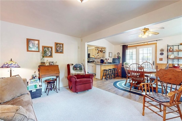 living area with a ceiling fan, wainscoting, and wood finished floors