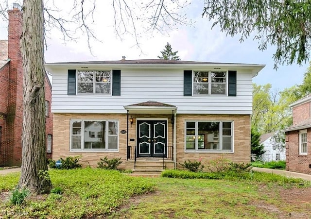 colonial inspired home with brick siding and a front lawn