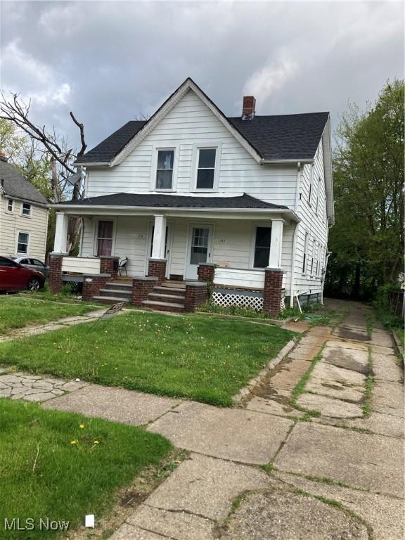 view of front of property featuring covered porch, a chimney, and a front lawn
