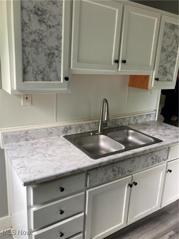 kitchen featuring a sink, light countertops, white cabinetry, and wood finished floors