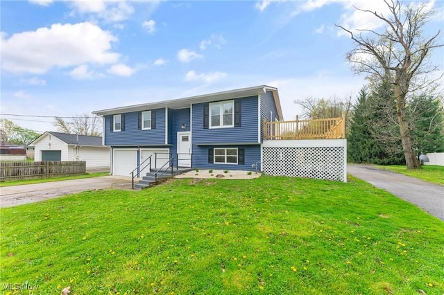 raised ranch with fence, an attached garage, driveway, and a front lawn