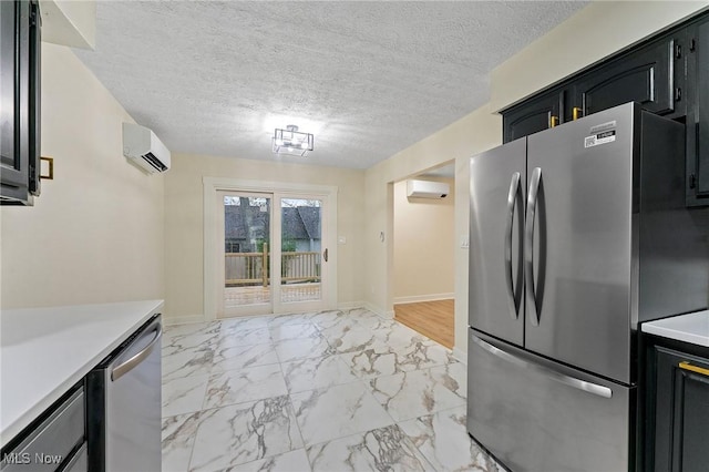 kitchen with appliances with stainless steel finishes, light countertops, an AC wall unit, marble finish floor, and dark cabinets