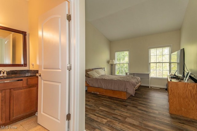 bedroom with a sink, baseboards, vaulted ceiling, and wood finished floors