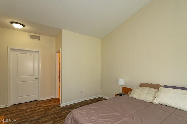 bedroom with baseboards, visible vents, and wood finished floors