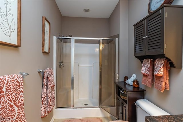 bathroom featuring a stall shower and toilet