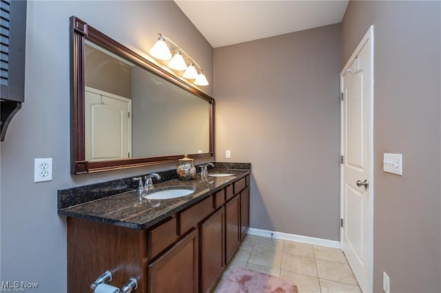 full bathroom featuring baseboards, double vanity, tile patterned floors, and a sink