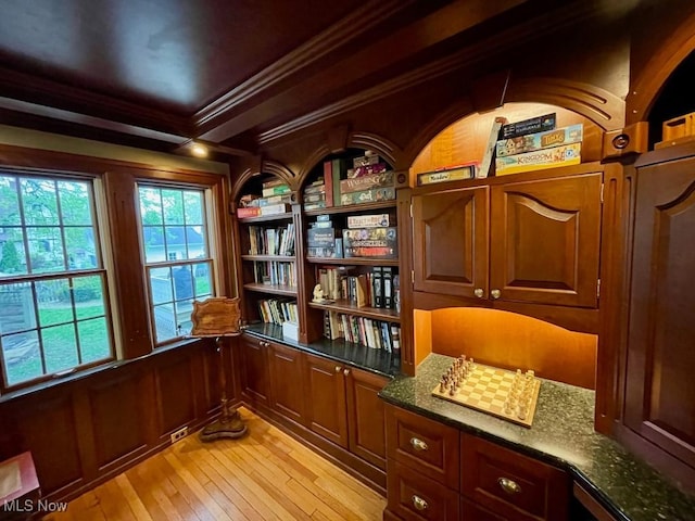 unfurnished room with ornamental molding, light wood-type flooring, and built in shelves
