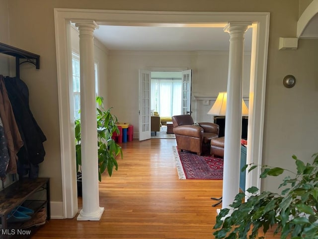 interior space with ornamental molding, light wood finished floors, and decorative columns