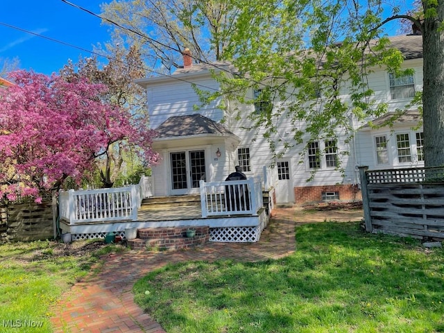 back of property featuring a lawn, a wooden deck, and a chimney
