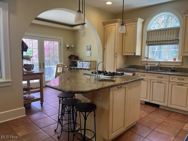 kitchen with arched walkways, a sink, and a breakfast bar